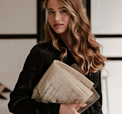 a woman in a black jacket holding a folder