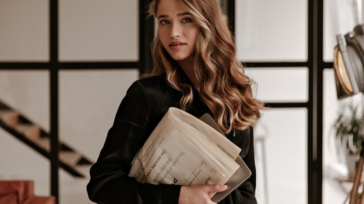 a woman in a black jacket holding a folder